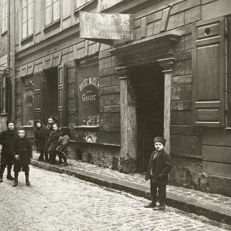 Savrtvitt foto på barn utanför ett Café i 1880-talets Stockholm