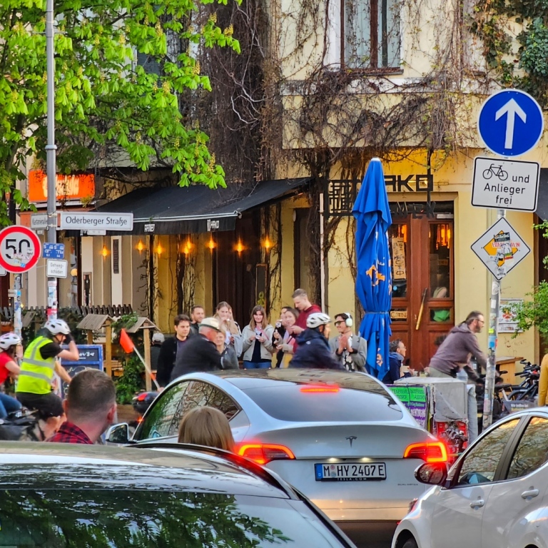 Bilar som väntar på att cyklar ska åka över en gata.