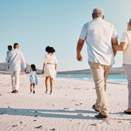 Personer går på en strand och håller varandra i handen