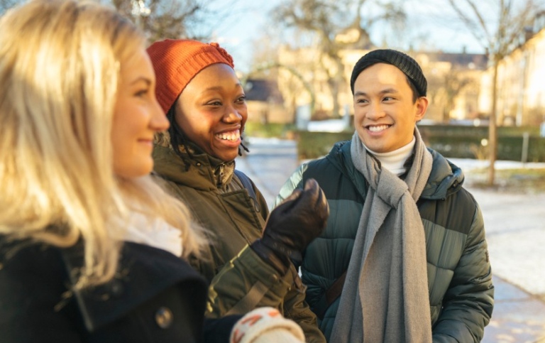 Students standing outdoors in winter clothes talking. 