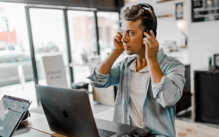 Young man with headphones in front of a laptop.