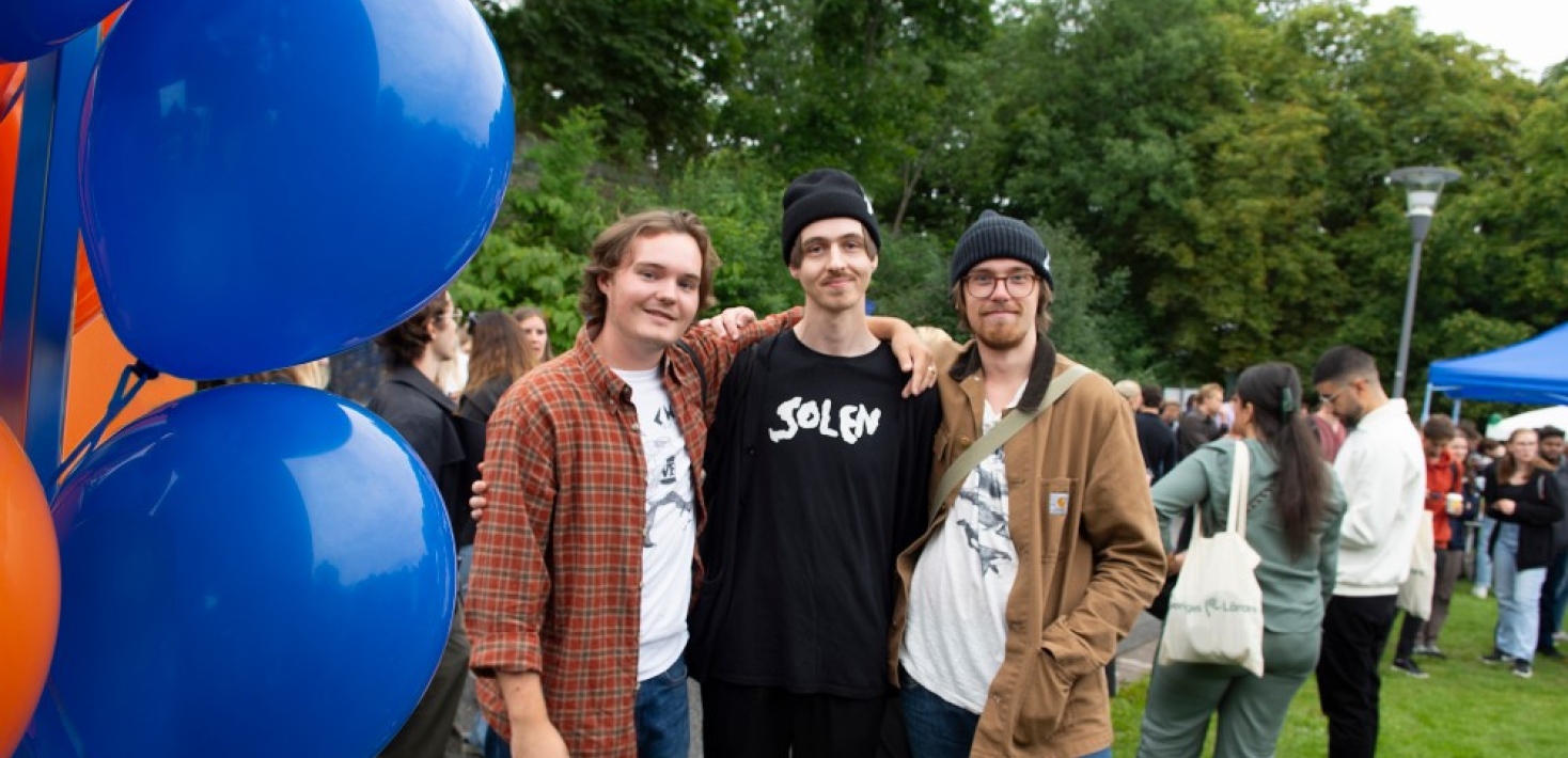 Tre killar bredvid ballonger på Välkomstdagen.