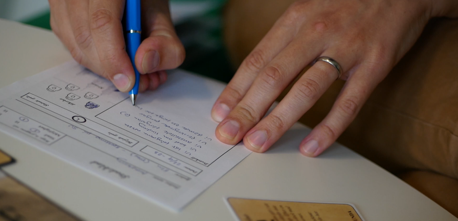 Närbild på händer som skriver på ett papper.