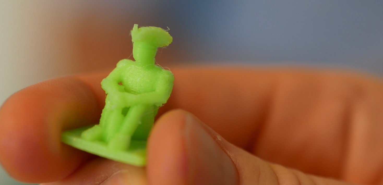 Närbild på en hand som håller i en liten grön plastfigur.