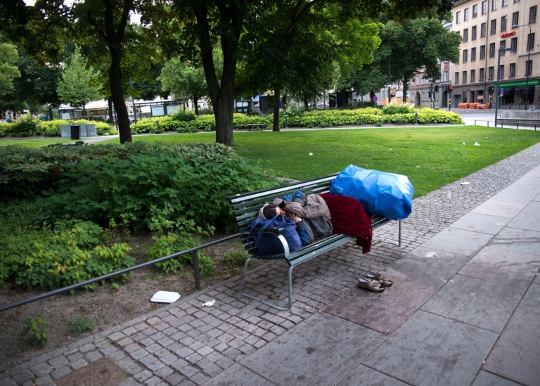 Hemlös person sover på en bänk i stan