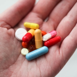 Genre photo: Lots of medicine in different colors in a person’s hand.