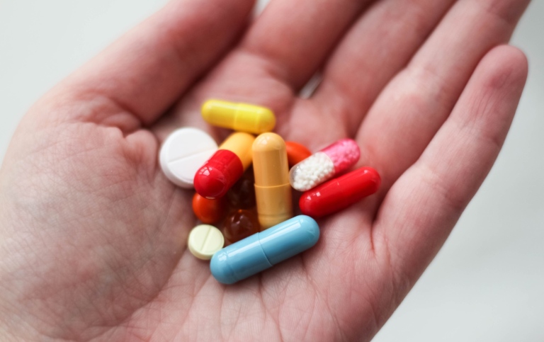 Genre photo: Lots of medicine in different colors in a person’s hand.