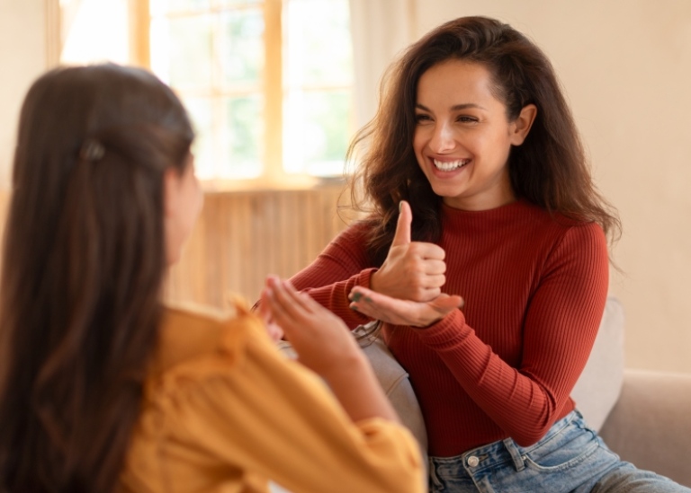 Happy Arabic deaf mute mother and daughter communicating at home using sign language.