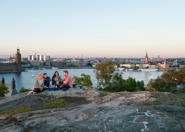 Studenter på klippa med vy av Stockholms stadshus..