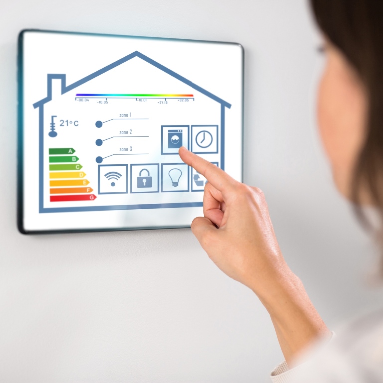 Genrebild som visar en kvinna som klickar på en skärm som reglerar temperatur etc i ett smart hem.
