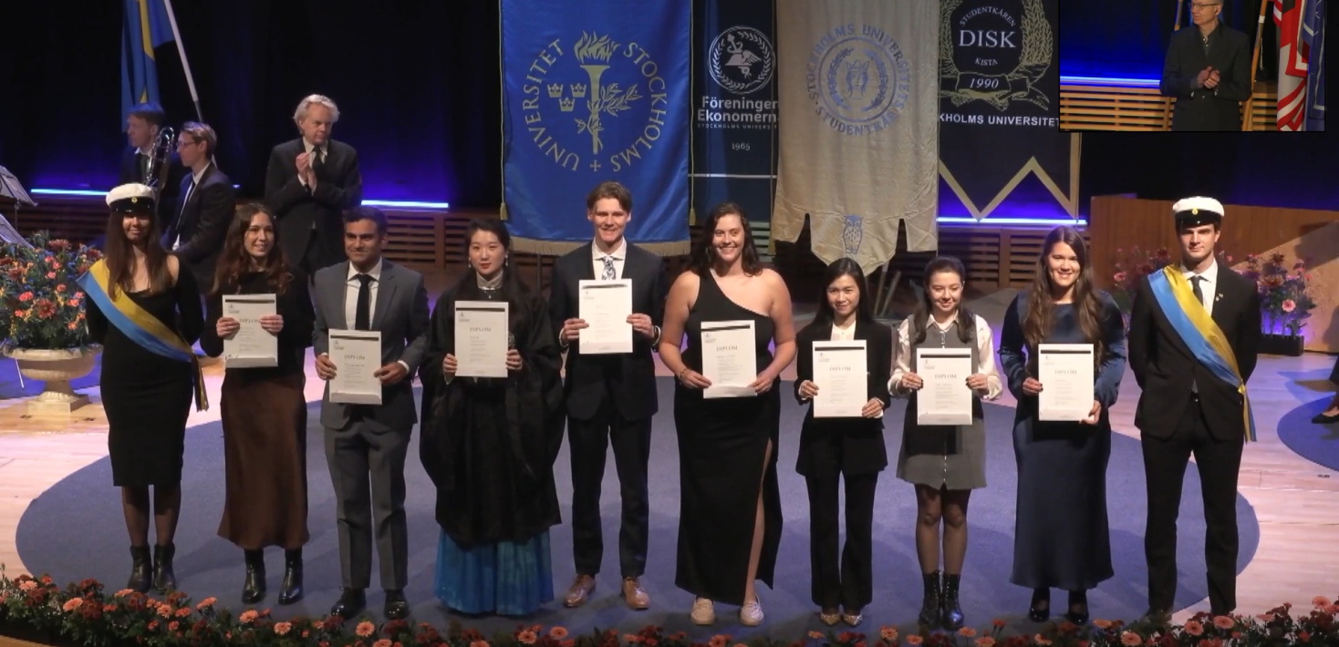 Grupp studenter på scenen med diplom i hand.