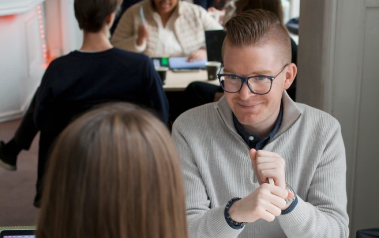 A student talking to a person sitting right across from him.