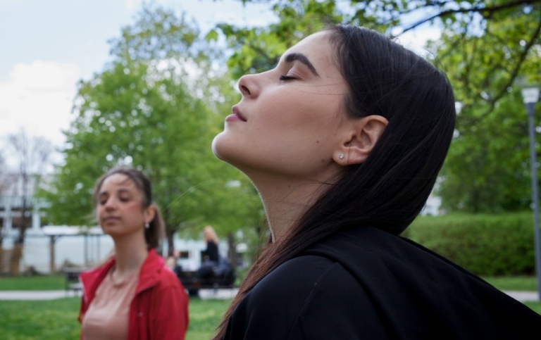 Student closing her eyes while lifting her head towards the sky.