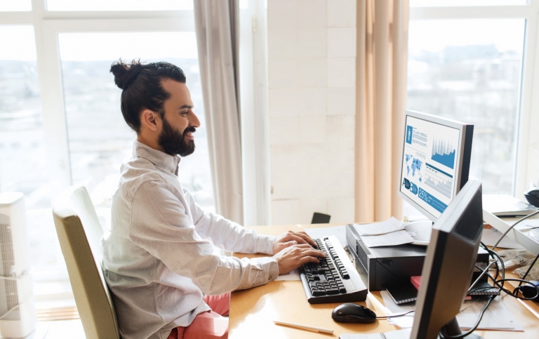 Young man sitting at a desk and writes on a computer