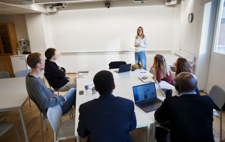 Kvinnlig lärare undervisar studenter i klassrum. 