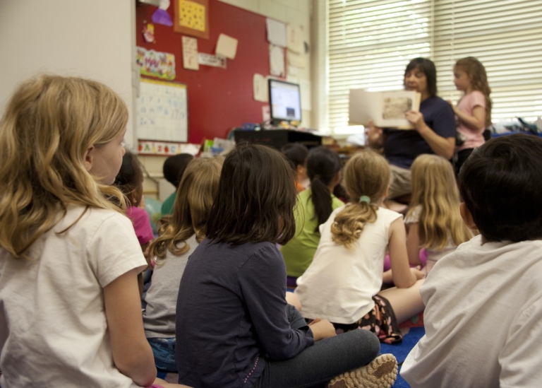 Lärare läser ur en bok för en grupp barn