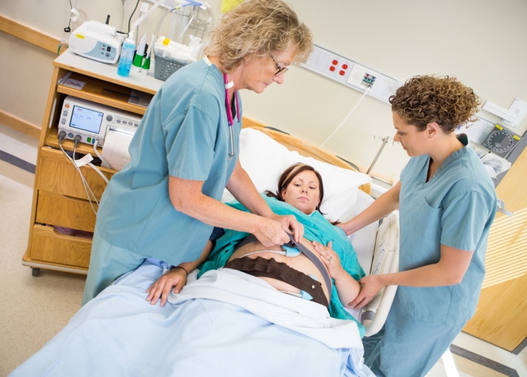 Nurses preparing pregnant woman for fetal heart rate.