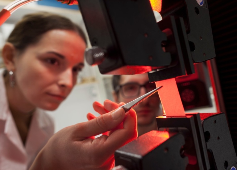 Två forskare studerar ett objekt i en maskin på ett labb.