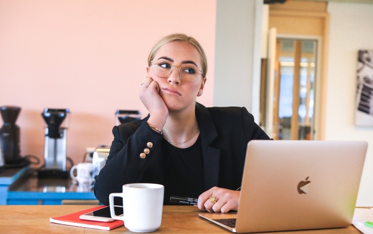 Tired woman at computer, with coffee.