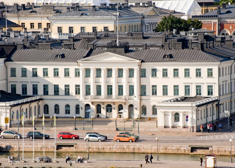 Vy över det vita presidentpalatset i Finland. Bilar i förgrunden.