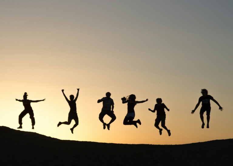 Silhouettes of six people jumping.