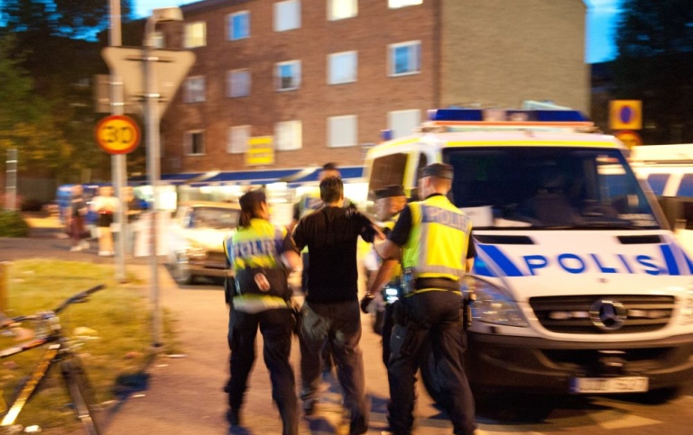 Poliser och polisbil på en gata i Sverige.