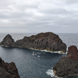 Cliffs in the ocean. White foam around cliff.