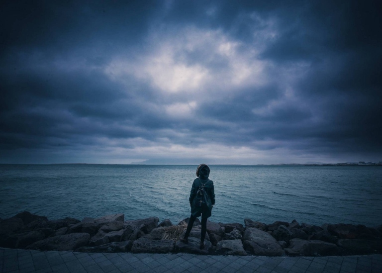Ung tjej som står och tittar ut över havet.