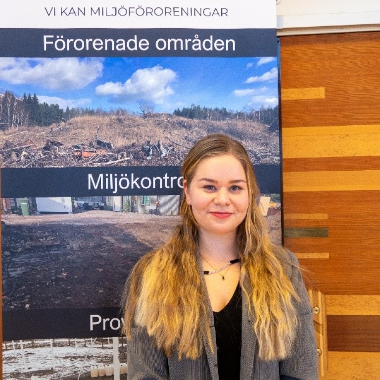 Ung kvinna med långt blont hår står framför skylt med texten "Vi kan miljöföroreningar"