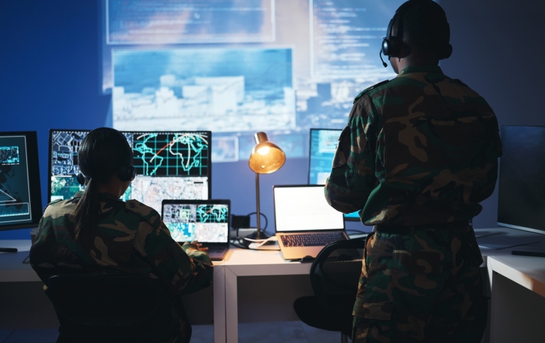 Two people in a military control room with technical devices.