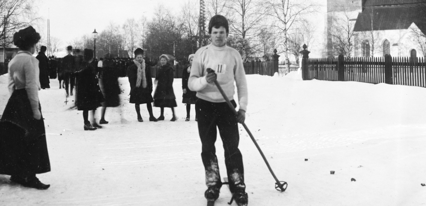 Svartvitt foto. Skidåkare och publik