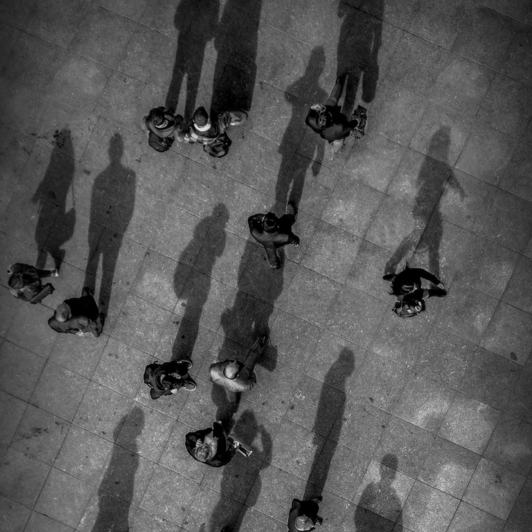 Black and white photo of a bunch of people and their shadows.