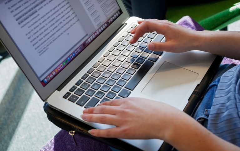 Närbild på student som skriver på en laptop.