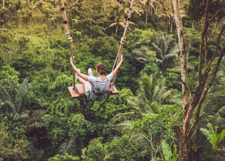 Woman on a swing in a tropical forest in Indonesia.