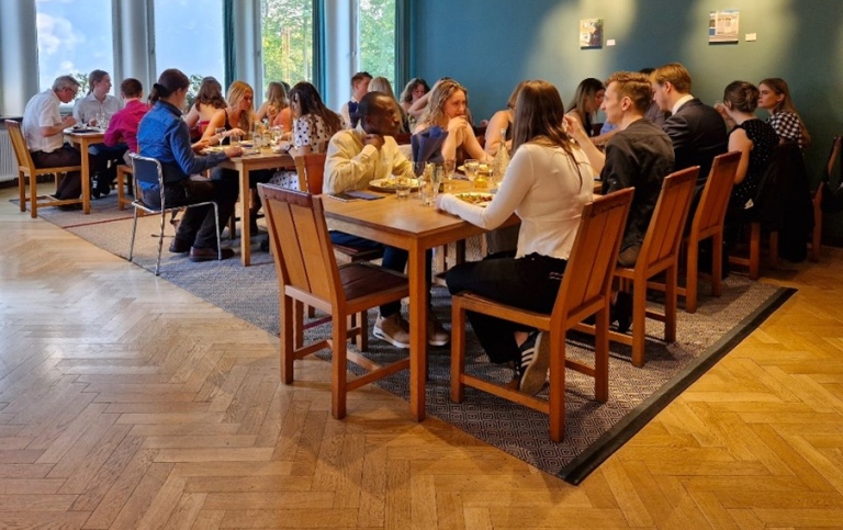 Ca 25 personer äter middag vid tre långbord.
