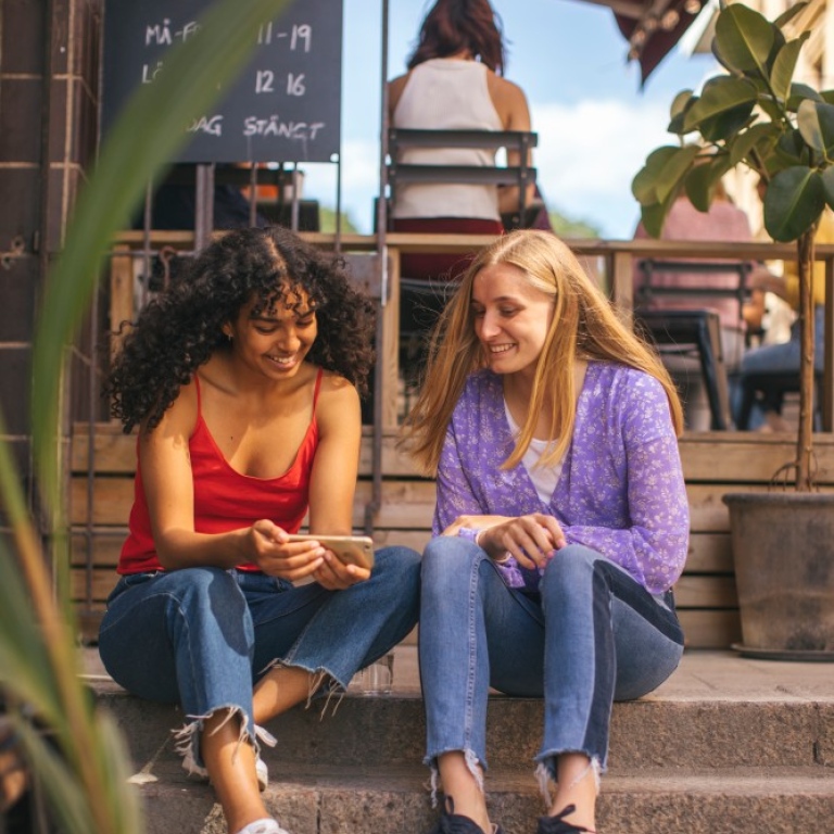 Foto: Niklas Björling. studenter sitter i en stentrappa samtalar och kollar på mobiltelef, Stockholm