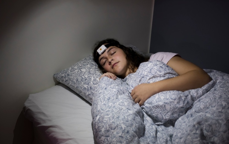 Ung kvinna sover i sömnlabbet.