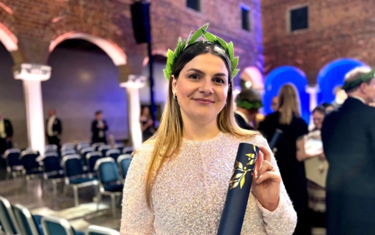 Aleksandra Adler, som disputerat i Översättningsvetenskap, med sin lagerkrans och diplom i Stockholms stadshus. Foto: Sofie Trosell, Stockholms universitet. Aleksandra Adler med sin lagerkrans och diplom.