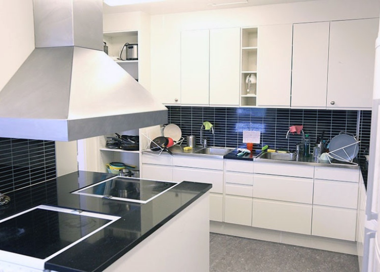 Kitchen with white cupboards and black tiles.