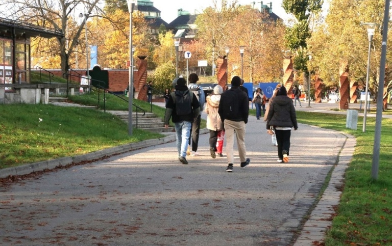 En grupp som går längs gångväg mot tunnelbanestation.