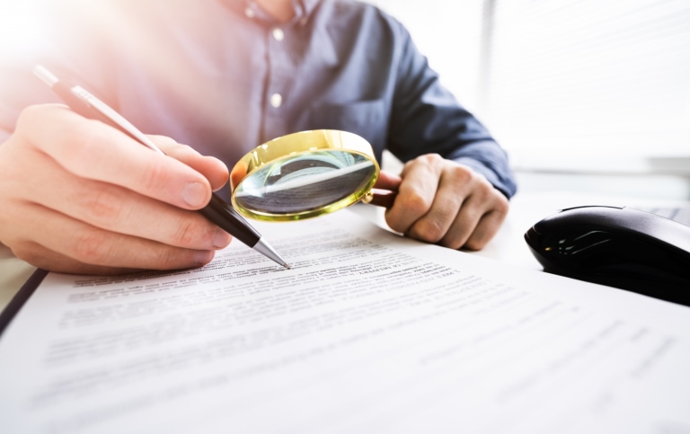 person holding a pen and a magnifying glass
