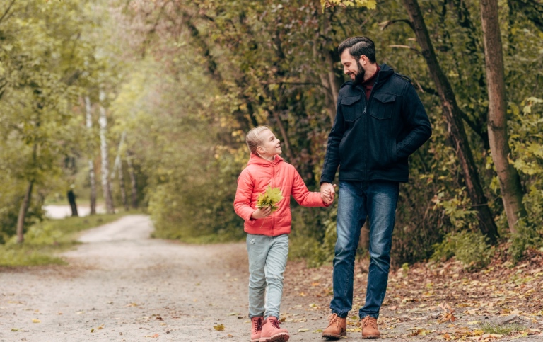 Far och dotter på skogspromenad en höstdag.