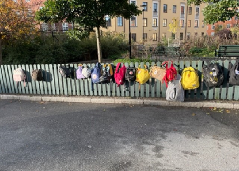 Färgglada ryggsäckar på rad på ett staket