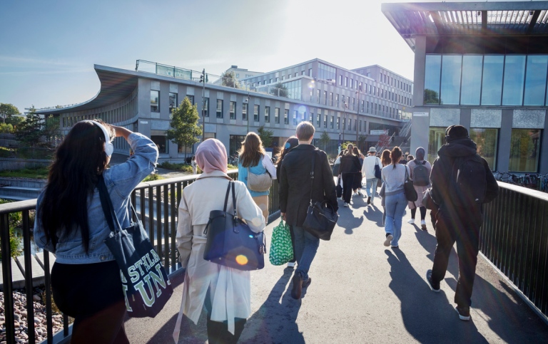 Flera personer på en gångbro mot Campus Albano