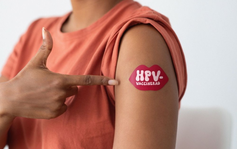 Närbild på en axel med ett plåster med texten HPV-vaccinerad.