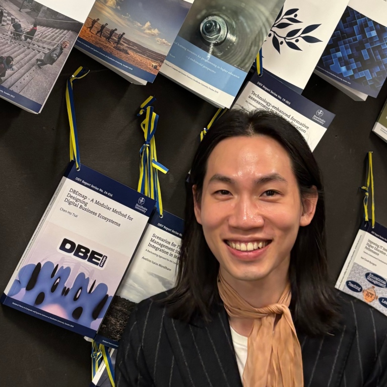 Daniel Chen Hsi Tsai står mot DSVs vägg där nya avhandlingar ”spikas” och görs tillgängliga.