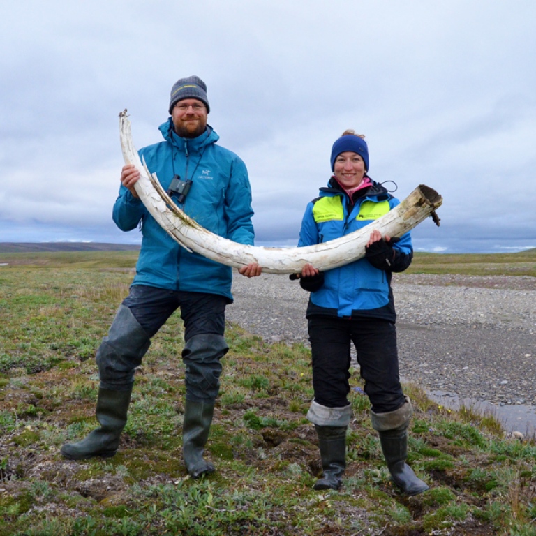 Two persons holding a large tusk