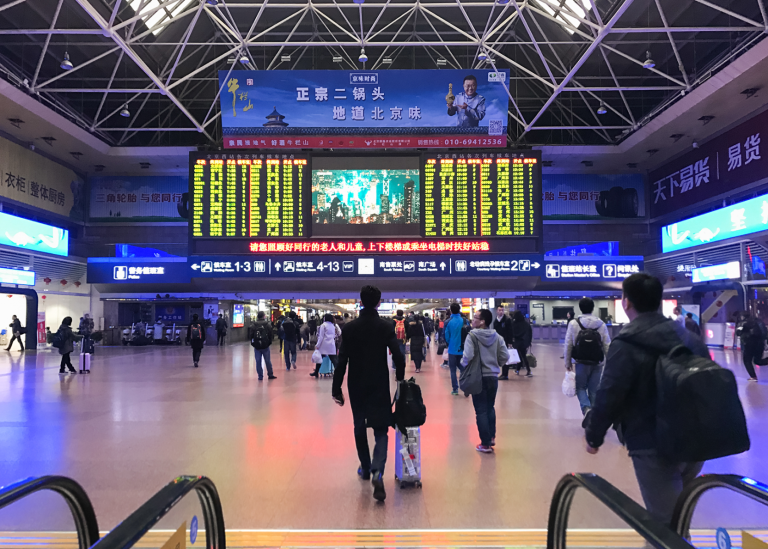 People in front of the announcement board at a train station in Beijing.