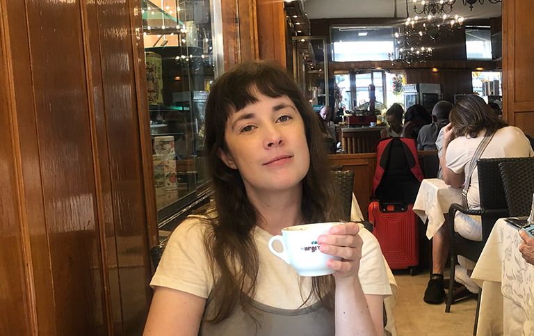 Adéle Askelöf sitter på restaurang i Rom med en kaffekopp i handen.