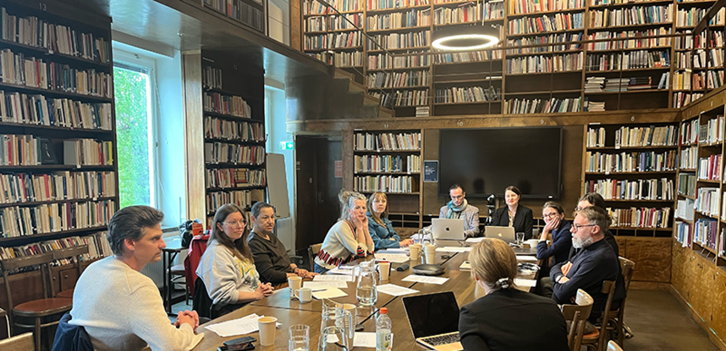 Ten persons around a table in a library.
